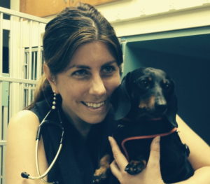 A photo of veterinary oncologist Brooke Britton, smiling and holding a black dachshund dog.