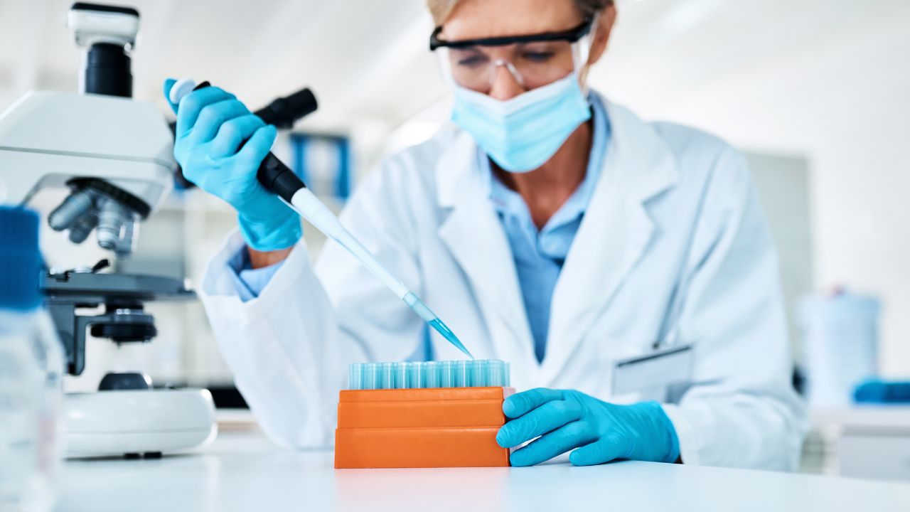 Dog cancer research is ongoing to find a new cancer treatment for dogs. This is a photo of a female scientist in a laboratory working with test tubes. 