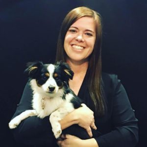 Photo of Jenny Fisher, smiling with a small dog with white and black fur.