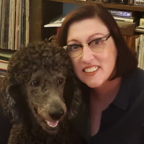 A female veterinarian hugging her black Poodle