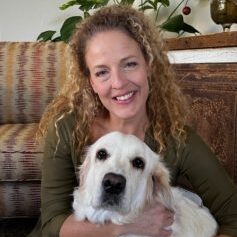 Curly haired woman hugging her senior Golden Retriever