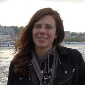 A female with long brown hair wearing glasses and black jacket