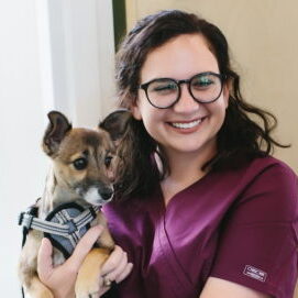 A photo of Dr. Sarah Brien, smiling, with her heart dog Evie, a chihuahua mix.